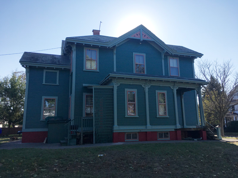 Front view of finished painted house with green siding and red detailed trim